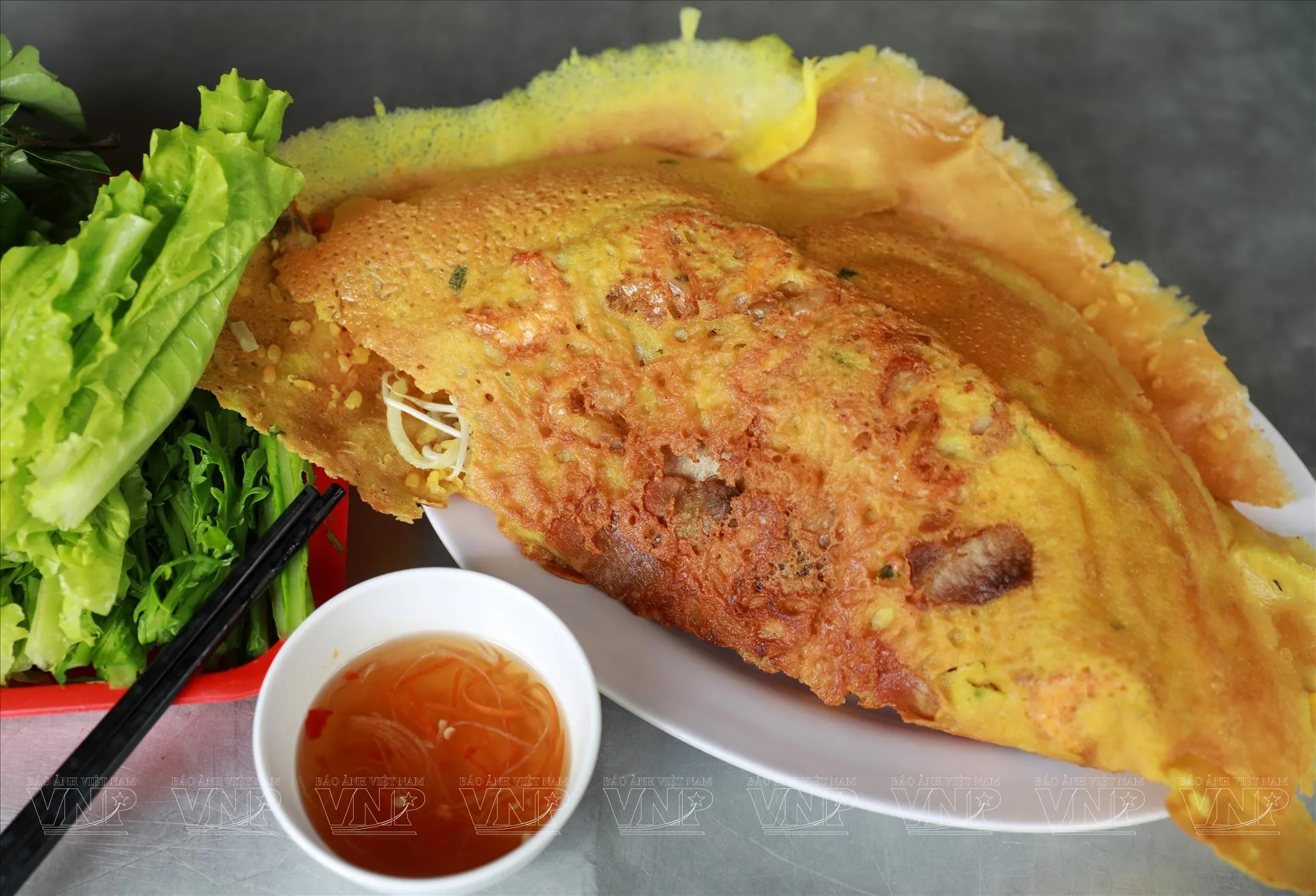 Bánh xèo vàng ươm được phục vụ cùng đĩa rau sống tươi ngon và chén nước chấm chua ngọt