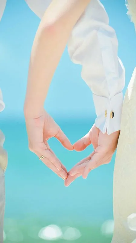 Ảnh đôi tay nắm chặt bên bờ biển với ánh nắng lãng mạn