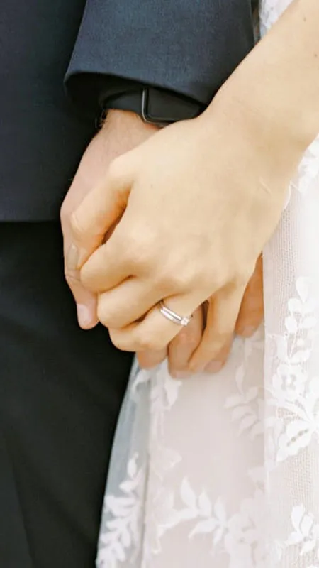Ảnh hai bàn tay với nhẫn cưới trên nền cảnh lãng mạn