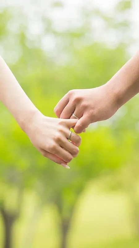 Ảnh nắm tay với nhẫn cưới và hoa, thể hiện niềm vui hôn nhân