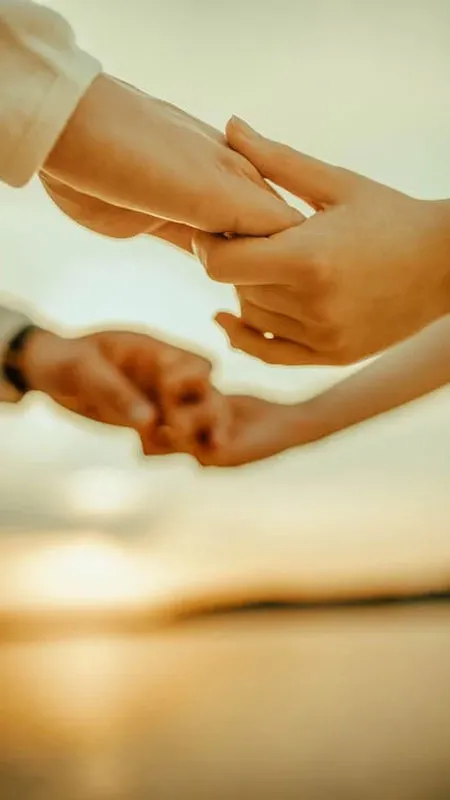 Ảnh nắm tay với nền biển xanh ngọc và cát vàng
