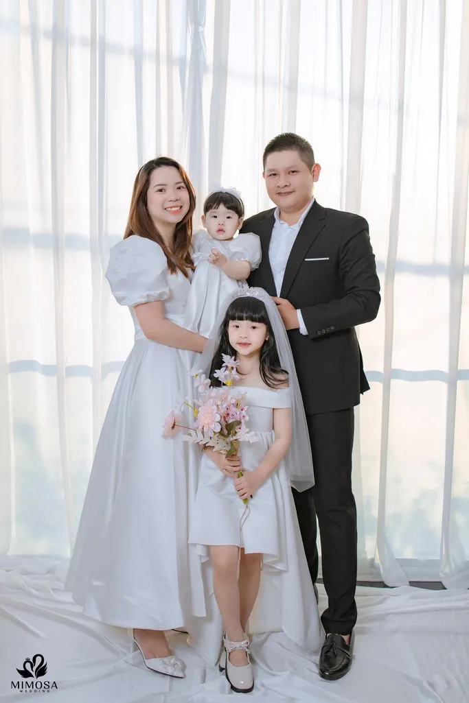 Hình ảnh gia đình 4 người chụp theo phong cách truyền thống, tạo dáng nghiêm túc