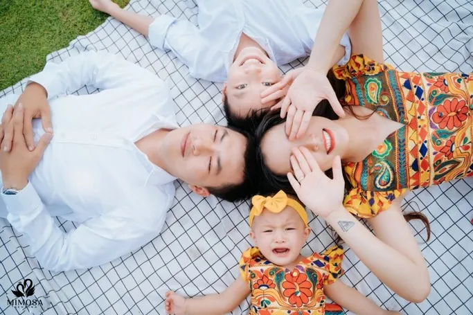 Gia đình 4 người nằm trên cỏ, tạo dáng thoải mái, phù hợp cả người lớn và trẻ em