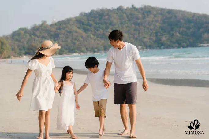 Gia đình 4 người vừa dắt tay vừa vui đùa trên bãi cỏ