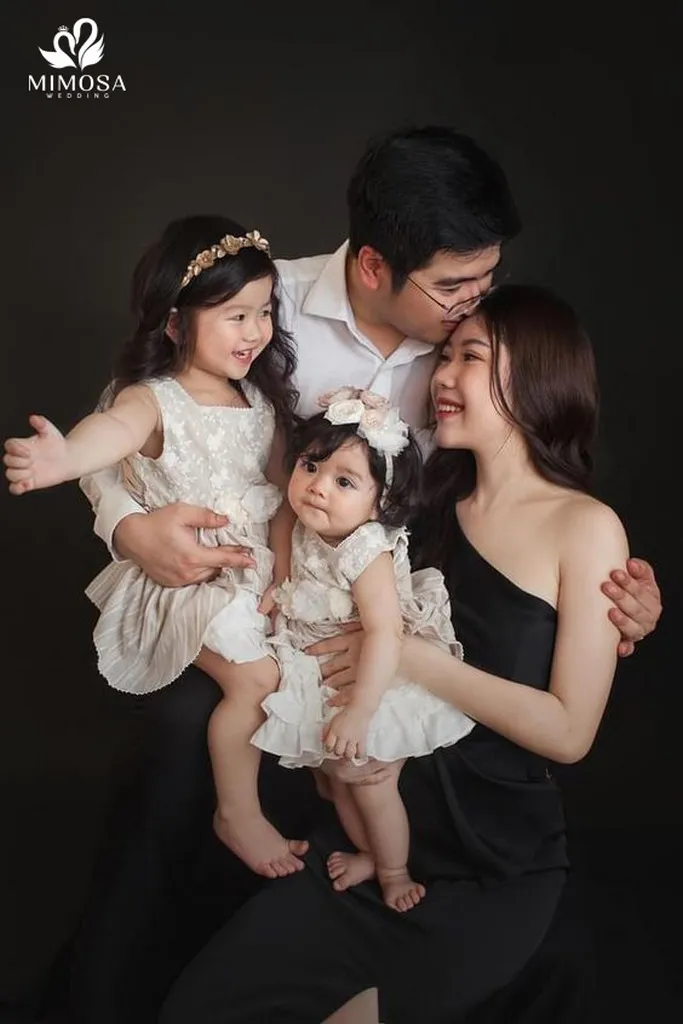 Hai bé gái xinh xắn tạo dáng cùng bố mẹ, thể hiện sự vui tươi