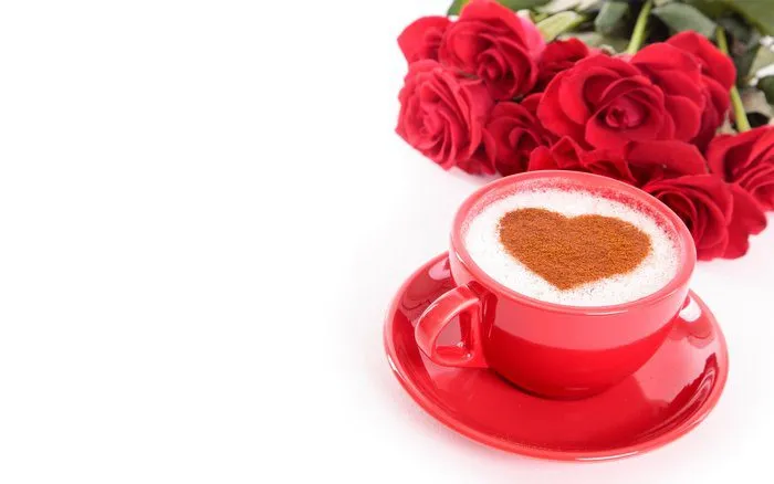 Ly cà phê đặt cạnh những bông hoa hồng tươi tắn, tạo nên khung cảnh thơ mộng và dịu dàng.