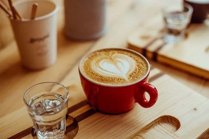 Capuchino với bọt sữa dày và bột cacao rắc trên mặt, trông rất hấp dẫn và mời gọi.