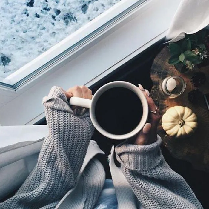 Ly cà phê đặt trên bàn với cảnh vật xung quanh mờ ảo, làm nổi bật sự tập trung vào khoảnh khắc hiện tại.