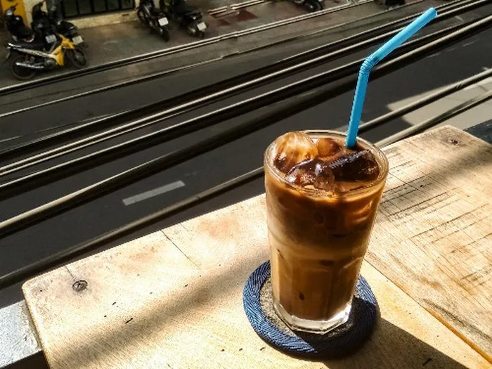 Ly cà phê sữa đá cao với tầng cà phê và sữa rõ rệt, những viên đá lớn làm tăng cảm giác mát lạnh.