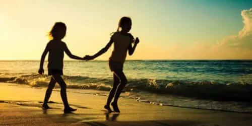 Hai chị em gái tay trong tay đi trên bãi biển, biểu tượng của tình cảm bền chặt