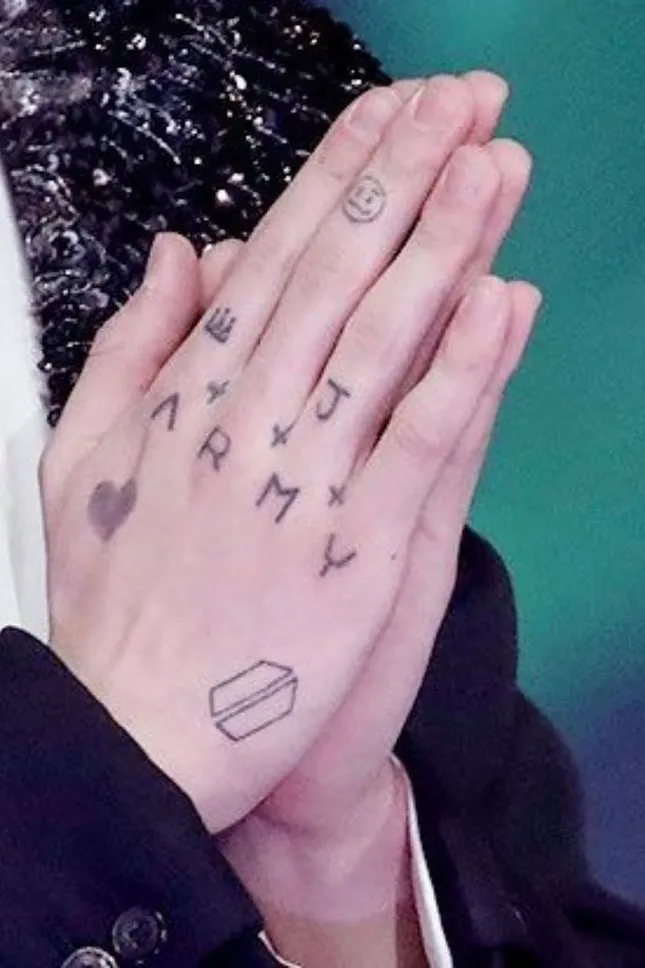 Hình xăm chữ ARMY và trái tim màu tím trên mu bàn tay phải của Jungkook thể hiện tình yêu với fan